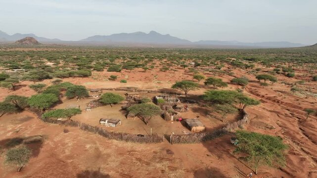 Aerial view of traditional samburu manyatta village surrounded by arid landscape and distant mountains, Wamba, Samburu, Kenya.