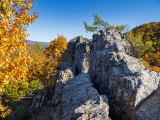 The rocky summit of Seneca Rocks, West Virginia, with clear, blue sky and mountains in fall colors.