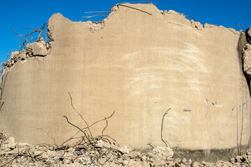 Part of concrete wall with reinforcing bars at demolition site.