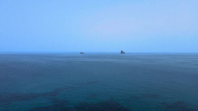A tranquil ocean view from El Gliaa, Bizerte, featuring calm blue waters and distant rocks on the horizon. The clear sky adds to the peaceful and picturesque atmosphere.
