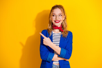 Stylish blonde woman with glasses and scarf pointing on yellow background