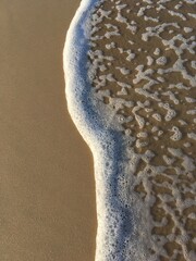 White sea foam on the golden sand of one of Mallacoota’s glorious ocean beaches, touched by the mellow glow of the late afternoon sun.