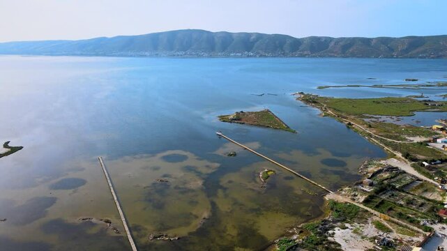 An overhead shot of Ghar El Meleh's wetlands and beach in Bizerte.The video captures the serene water bodies,small islands,and the sandy beach with straw huts,offering a tranquil and picturesque view.
