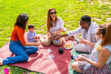 Friends playing cards at a picnic in the park