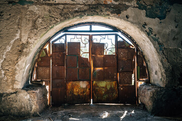 Rusty metal gate blocking arched entrance of abandoned building highlighting decay and isolation...