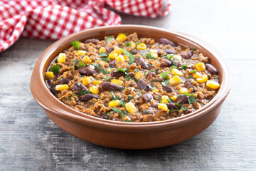 Traditional Mexican Chili con carne. Minced meat and vegetables stew in tomato sauce on wooden table