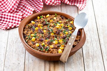 Traditional Mexican Chili con carne. Minced meat and vegetables stew in tomato sauce on wooden table