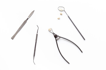 Obraz premium Dental crowns with steel instruments for dental prosthetics, top view. Dentist desk, white background
