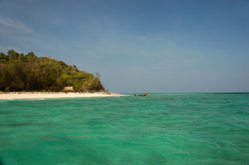 Limestone karst islands of Hong Island rise from the turquoise waters of the Andaman Sea under a clear blue sky in southern Thailand