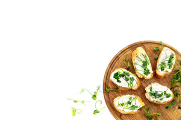Toasts with fresh sprouting microgreens and cream cheese on wooden board, top view