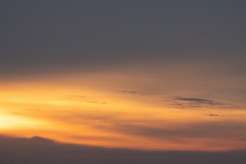 An orange and beautiful sky with a stunning cloudscape at dusk, just before sunrise. The wonderful spring sunrise creates a mesmerising backdrop, with clouds scattered across the sky.