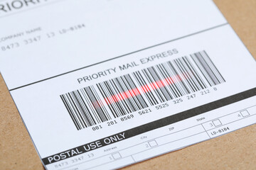 Parcel with label, closeup. Red laser light on barcode for scanning