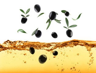 Black olives and green leaves falling into cooking oil on white background