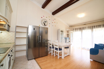 Kitchen studio with double-door refrigerator, table, chairs, sofa and cabinets