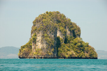 Naklejka premium Limestone karst islands of Hong Island rise from the turquoise waters of the Andaman Sea under a clear blue sky in southern Thailand