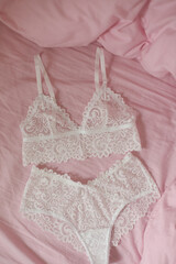 Woman's silk erotic lingerie on the white bed sheets. Valentine's day concept. Lace sexy female underwear. Beauty, fashion blogger concept. Female bra, panties, erotic clothes. Lingerie advertising
