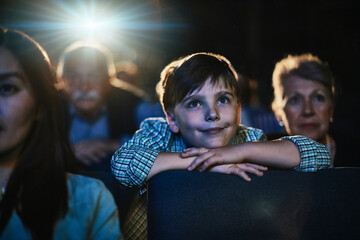 Young boy watching movie in cinema with grandparents