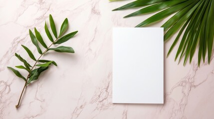 Blank paper, greenery on a pink marble background