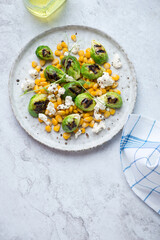 Plate with corn, grilled Brussels sprouts and cheese on a white stone background, vertical shot with space, top view