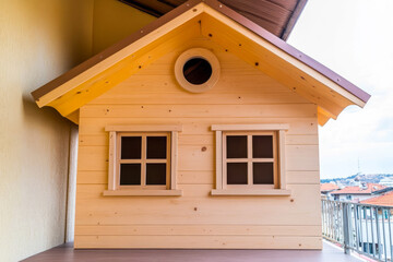 Charming wooden playhouse featuring yellow roof and large windows on balcony