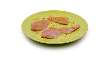 Three pieces of fresh - raw chicken on a green plate salted with dry vegetable seasoning. Fresh chicken meat ready for grilling or pan-frying. Raw chicken meat.