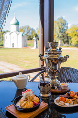 Russian traditions. Tea drinking over a samovar. Still life with bagels and Russian treats on the veranda against the background of the Transfiguration Cathedral in Pereslavl-Zalessky.