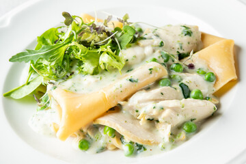 Creamy pasta with chicken, peas, and fresh greens. The dish is beautifully plated, showcasing vibrant colors and a rich sauce, perfect for a delicious meal.