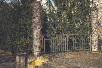 Overgrown pillars and fence surrounded by lush greenery in a tranquil outdoor setting