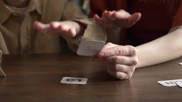 mother teaches her young son to speak using flashcards in the living room at home.