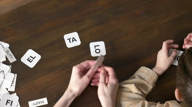 mother teaches her young son to speak using flashcards in the living room at home.