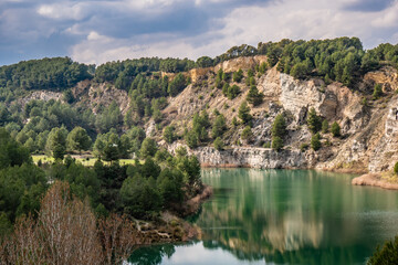 Fototapeta premium Beautiful turquoise lake next to an arid Mediterranean mountain with a recreational area.