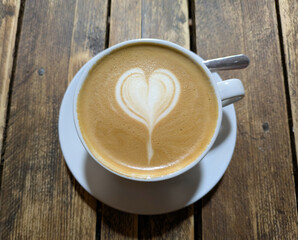 Close Up of an Oat Milk Latte Coffee in White Cup on a Rustic Wooden Table Background with Love Heart