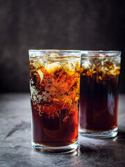 Cola soft drink with ice cubes, soda fizzy drink in Cold two glass on gray background