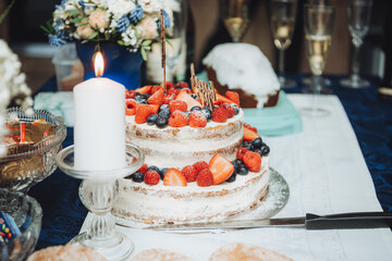 Festive cake with white cream, decorated with raspberries and strawberries