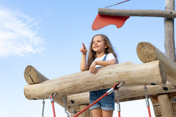 Curious young sailor. Little girl playing outdoors at the playground in the park. Imagination on a...