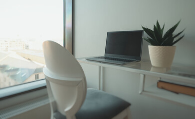 Laptop by the window in an office workspace.