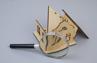 Ruins of house under magnifying glass on gray background. Accident investigation concept.