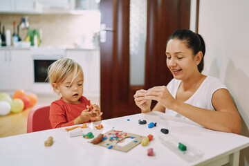 Naklejka premium Mom and her little daughter sculpt different figures from plasticine 