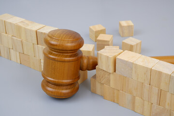 Wooden judge gavel breaking wooden wall on gray background. 