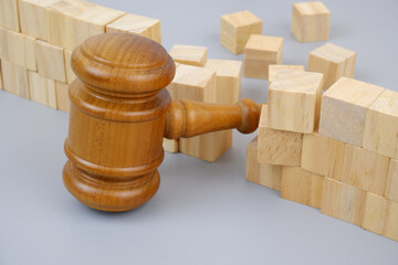 Gavel and broken wall on gray background.