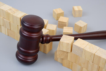 Wooden gavel breaking wall on gray background. 