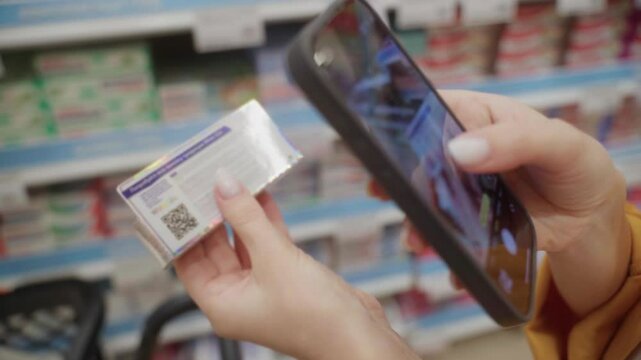 A person holds a toothpaste package with a QR code and uses a smartphone to scan it in a grocery store aisle. The focus is on the interaction with the product's packaging.