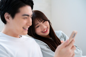 Fototapeta premium 笑顔でスマホを見る日本人男女
