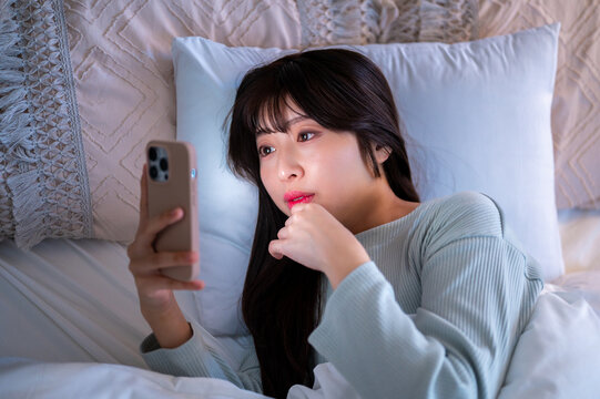 夜更かししてスマホを見る日本人女性