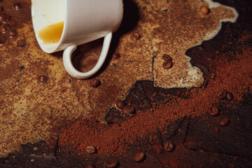 Coffee still life. Grains and ground coffee in detail scattered on a dark table with spilled milk