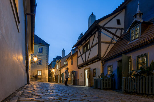 Prague, Czechia - 03 November 2022: View of charming Golden Lane with picturesque cobblestone street and illuminated lanterns at night, Prague, Bohemia, Czechia.