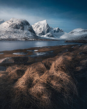 View of Morpheus beach with majestic snow-capped mountains and tranquil water, Napp, Nordland, Norway.
