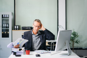 Frustrated  businessman working on a laptop computer sitting at his working place