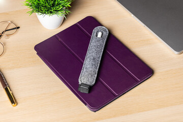 Handmade Felt gray case for stylus lies on tablet in purple case. Stylus and tablet on light wooden...