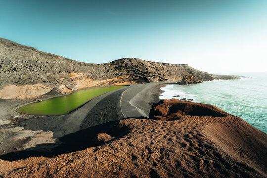 View of picturesque green lagoon surrounded by tranquil cliffs and beautiful beach, El Golfo, Lanzarote, Spain.